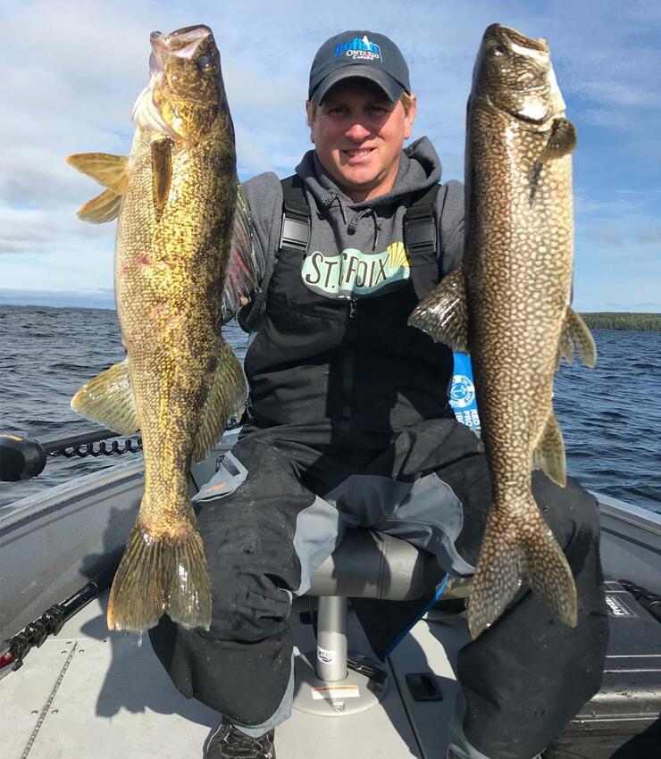 angler holding walleye and lake trout