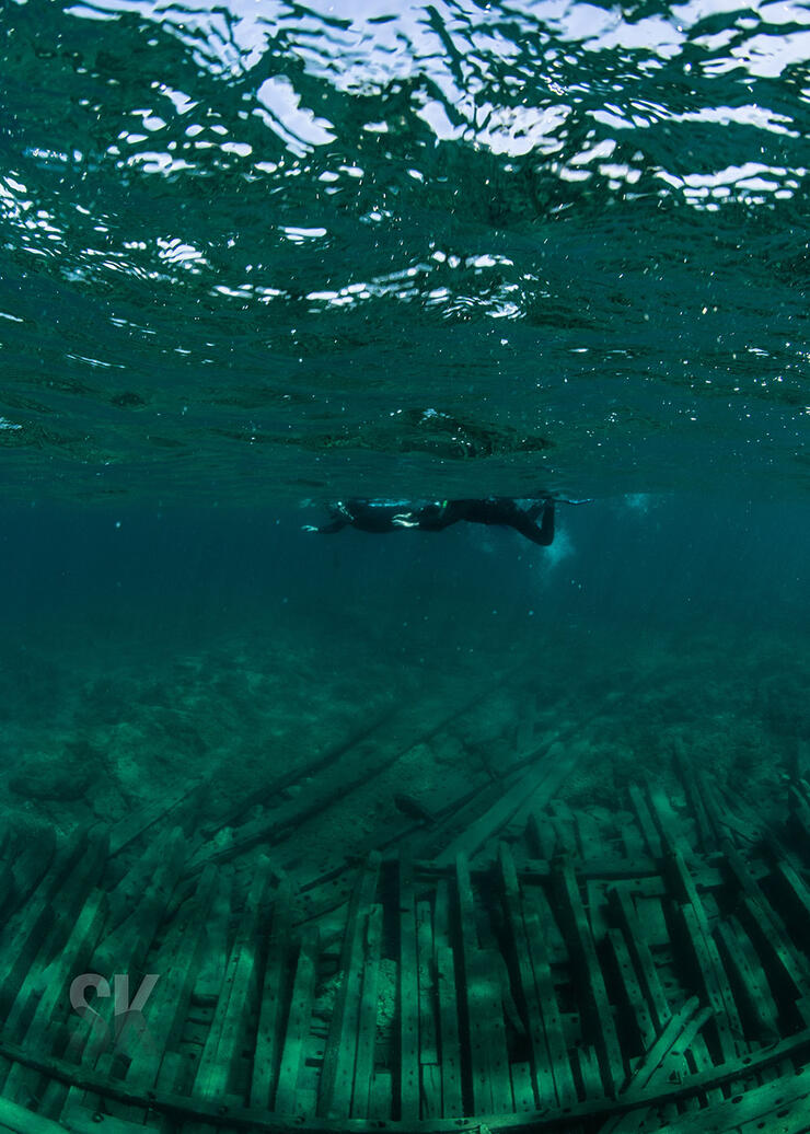 scuba diver floats at the surface looking down at a shipwreck