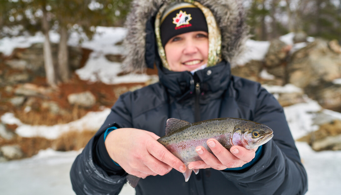 A young girl holds up a winter walleye she caught ice fishing